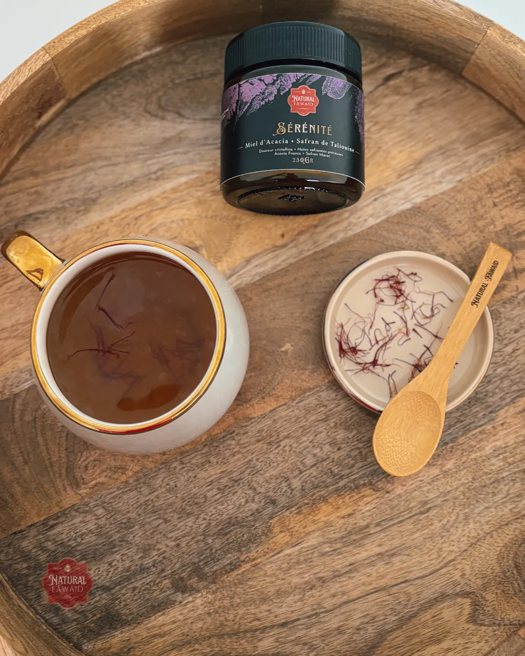 Miel Sérénité versé dans une tasse artisanale avec pistils de safran, plateau bois naturel
