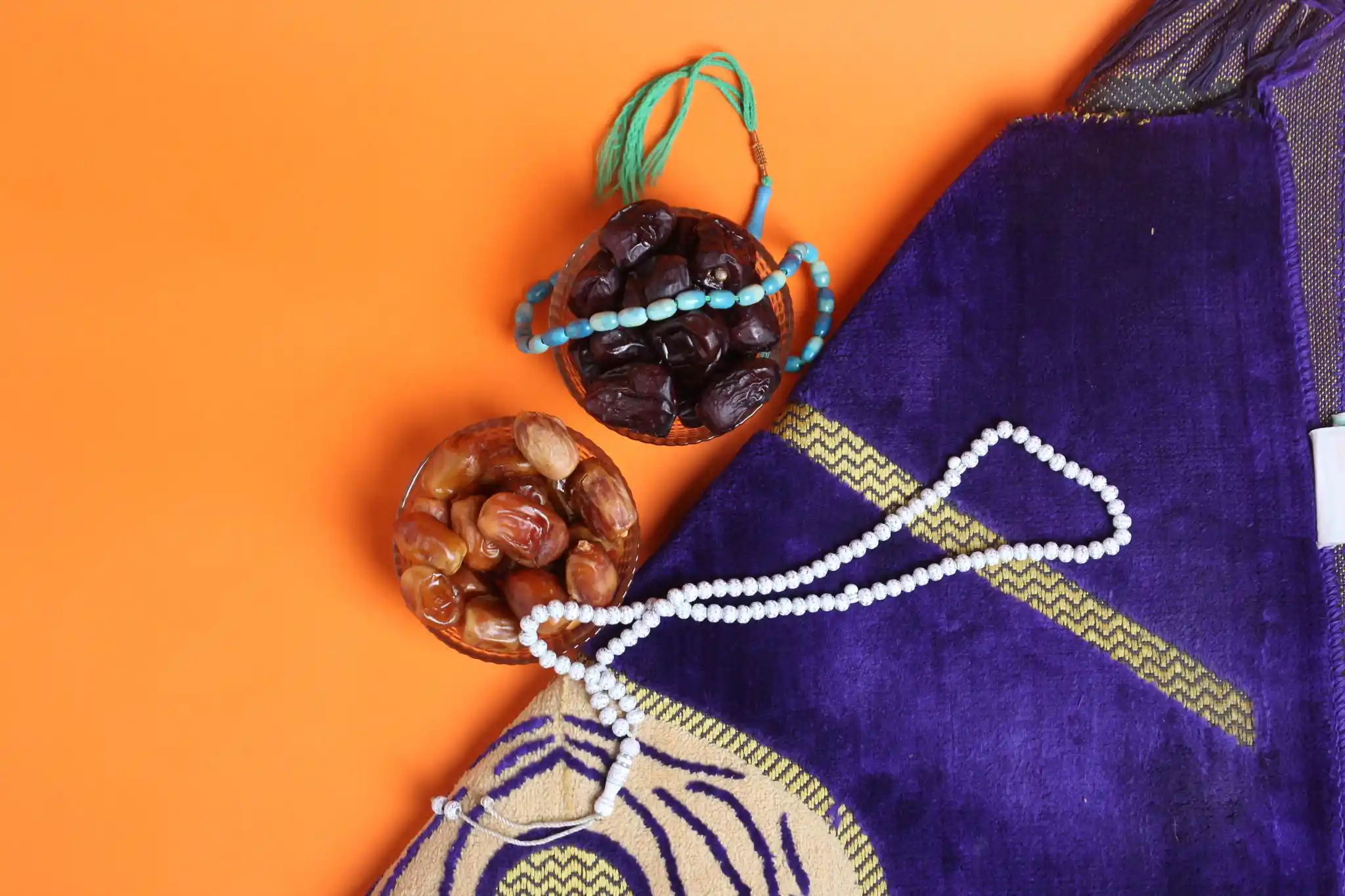 Deux bols de dattes Ajwa et sukari avec chapelets de prière sur fond clair