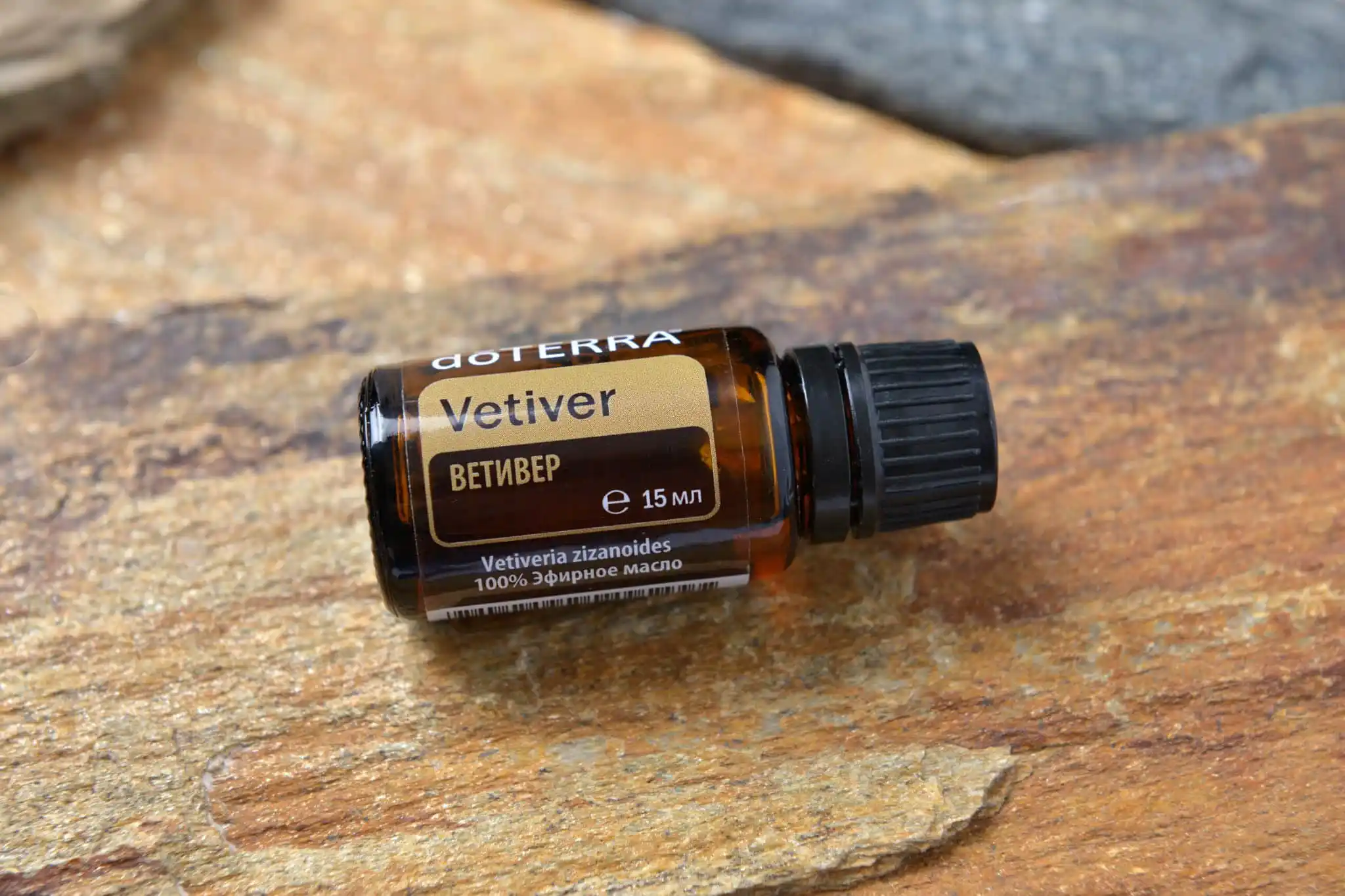 Flacon en verre ambré d’huile essentielle de vétiver posé sur une surface en pierre naturelle.