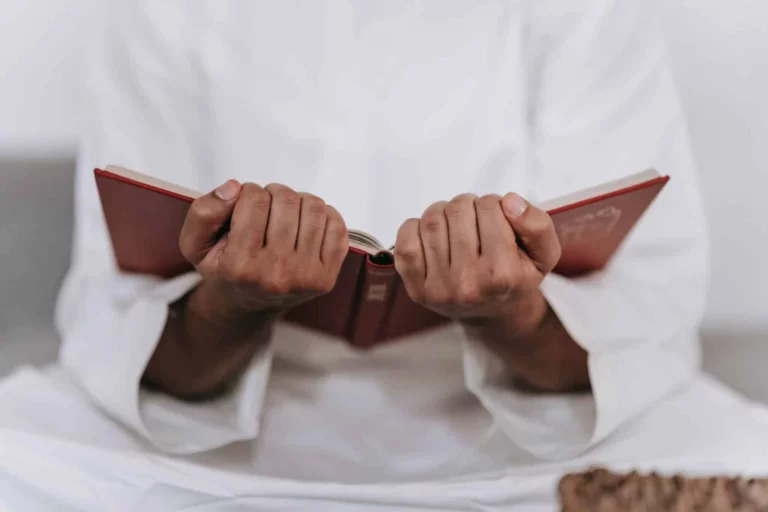 Personne en vêtement blanc tenant un livre ouvert et lisant un ouvrage de référence sur les habitudes de vie prophétiques